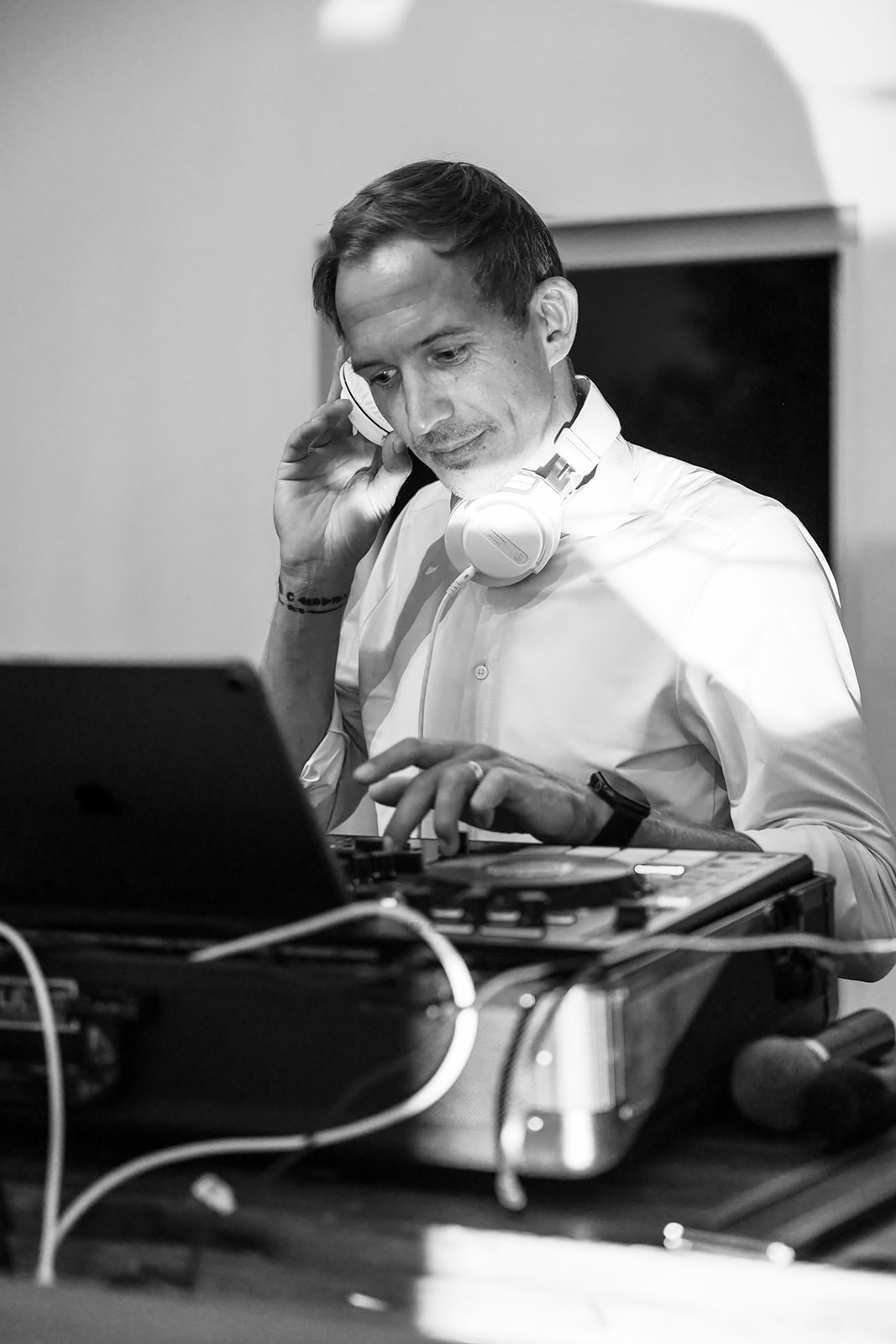 Schwarzweißbild: Chris Carter am DJ-Pult, eine Hand am Kopfhörer, die andere am Controller
