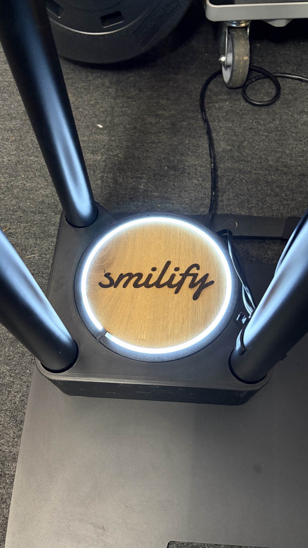 Bodenplatte der Smilify Fotobox mit leuchtendem LED-Ring um die Holzscheibe mit smilify-Schriftzug