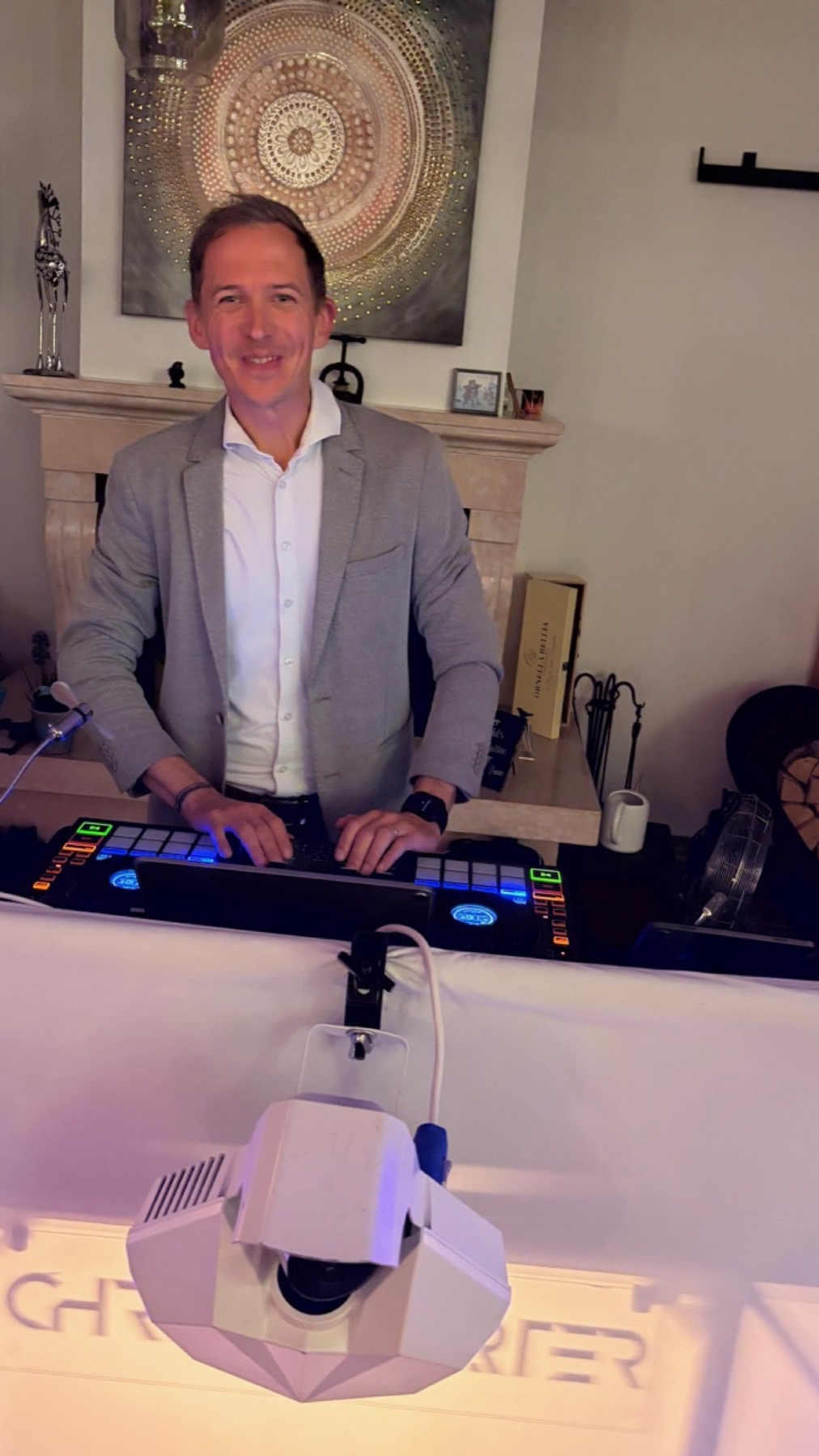 Chris hinter dem DJ-Pult mit Logo und Lichteffekt