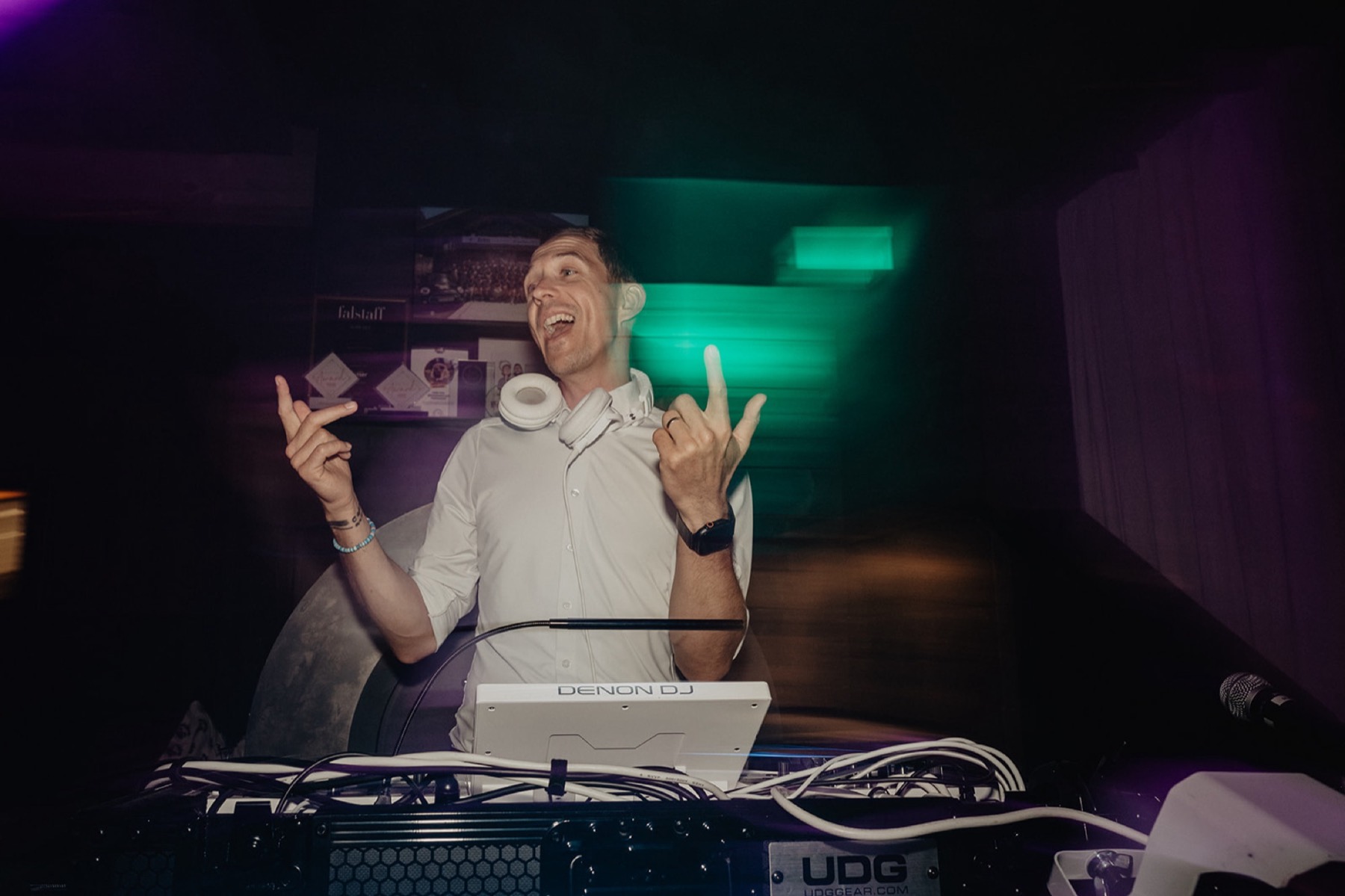 Chris am Pult mit Kopfhörer um den Hals, grün-violettes Licht