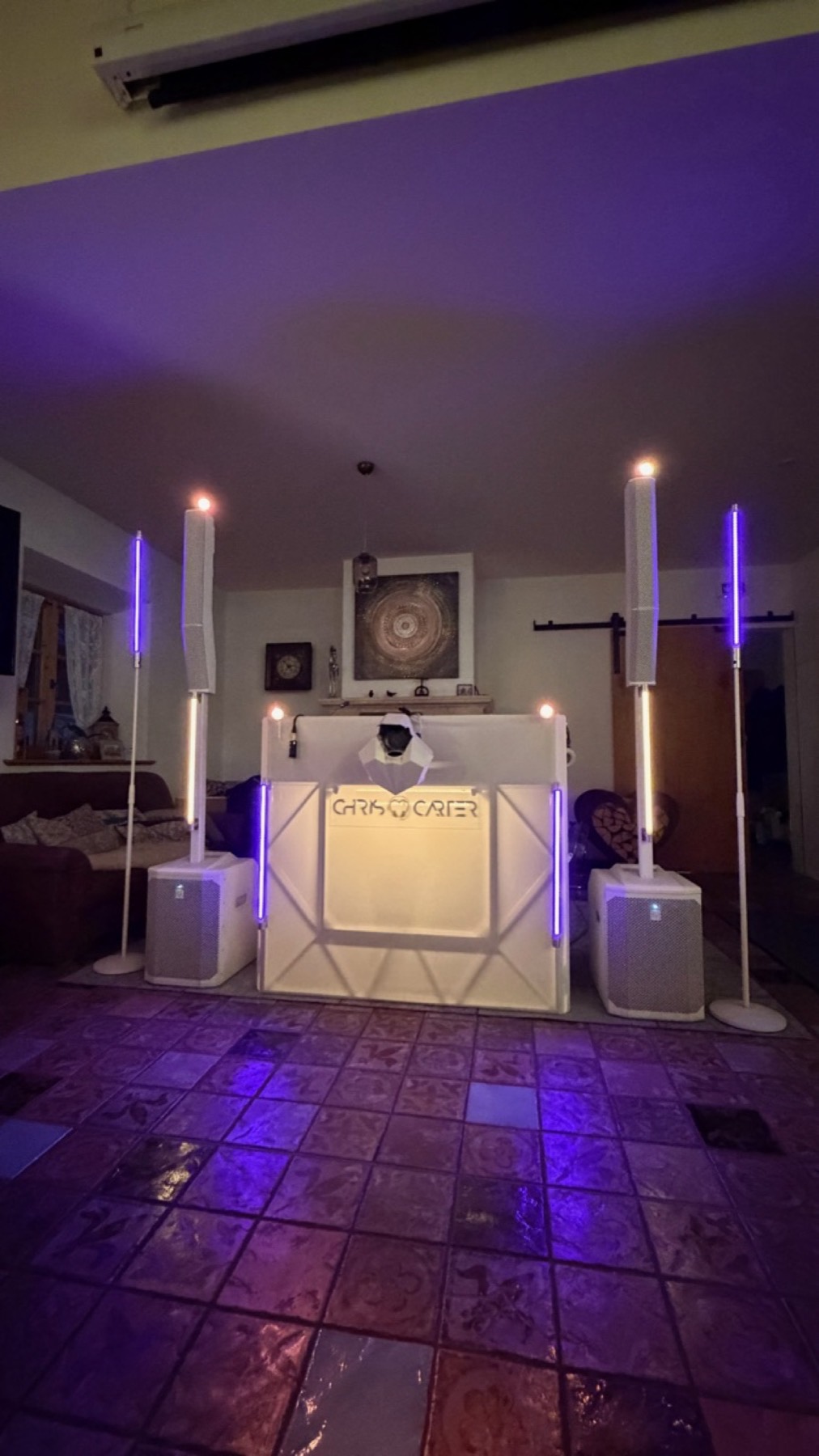 DJ-Pult mit Lichtstangen in Violett, Tanzfläche mit farbigem Licht auf den Fliesen