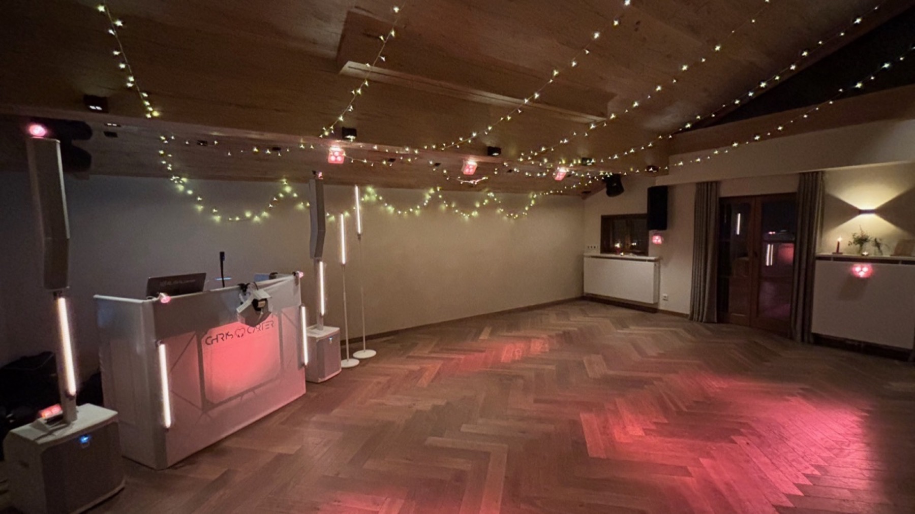 Festsaal mit Lichterketten, DJ-Pult und Lichtstangen, rosa Lichtflecken auf der Tanzfläche