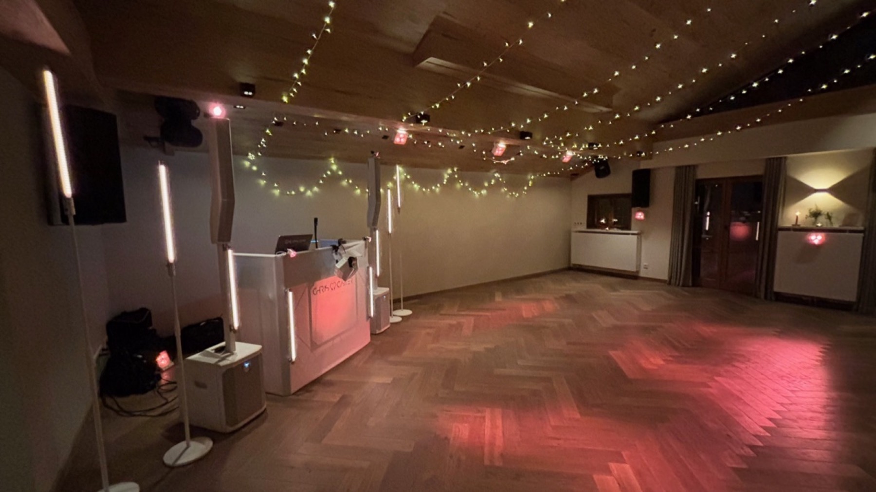 Zweite Ansicht des Saals mit DJ-Pult, Lichtstangen und farbigem Licht auf dem Parkett