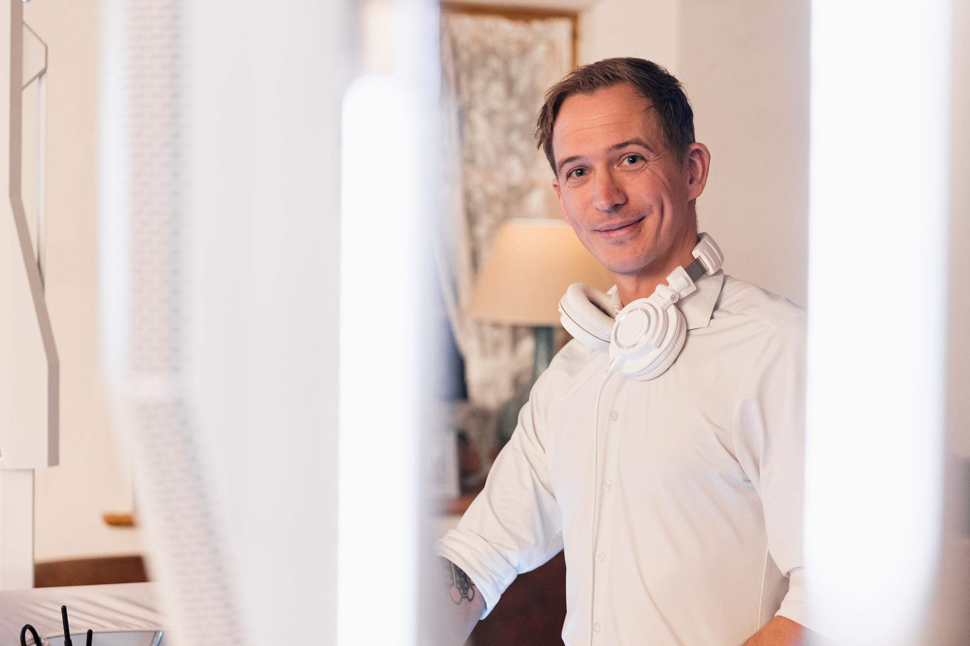 Chris Carter mit Kopfhörern um den Hals am weißen Pult
